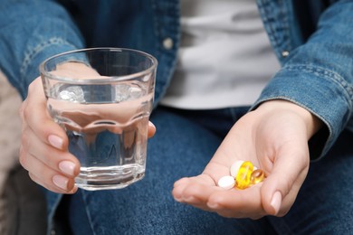 Woman with glass of water and pills, closeup view