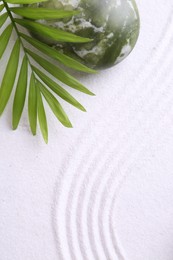 Photo of Zen concept. Stone and pattern on white sand, top view. Space for text