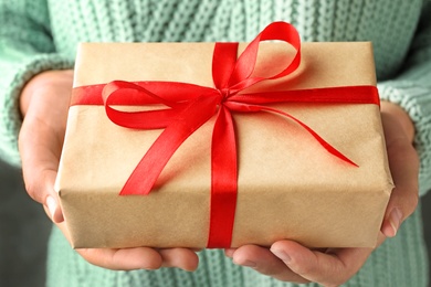 Photo of Woman holding beautiful Christmas gift with bow, closeup