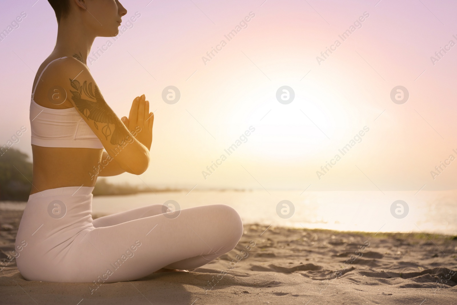 Image of Young woman meditating on beach at sunrise, closeup. Practicing yoga