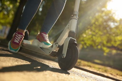 Photo of Woman riding electric kick scooter outdoors, closeup