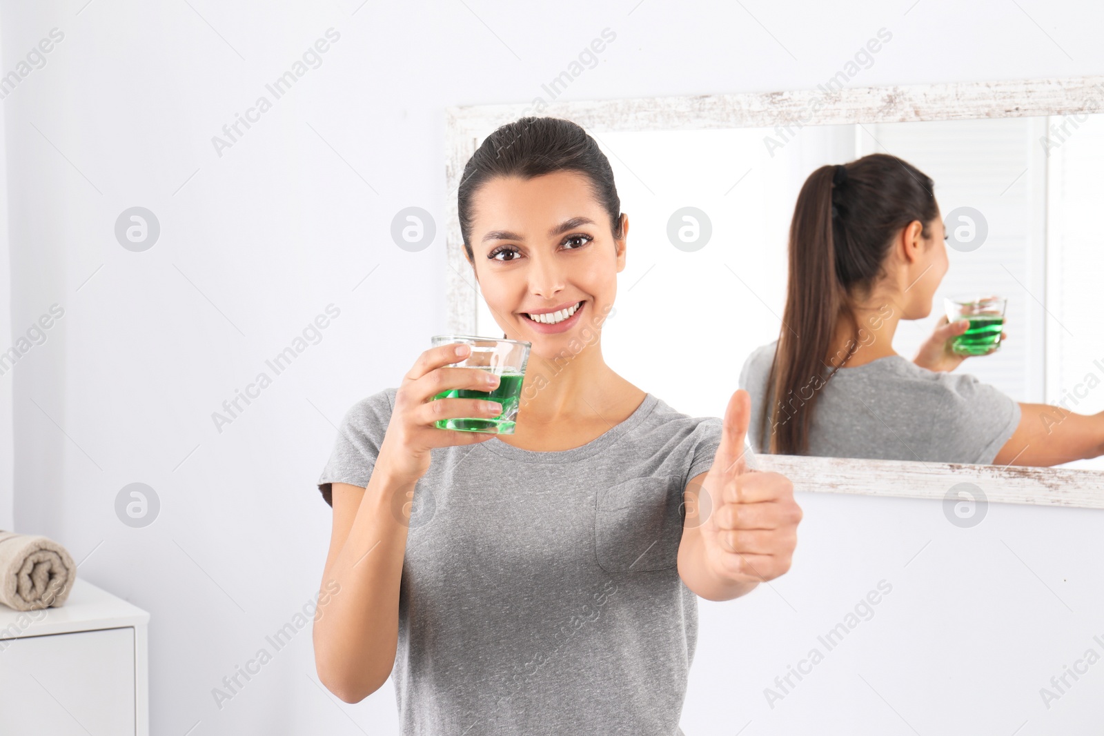 Photo of Young woman with mouthwash in bathroom. Teeth and oral care