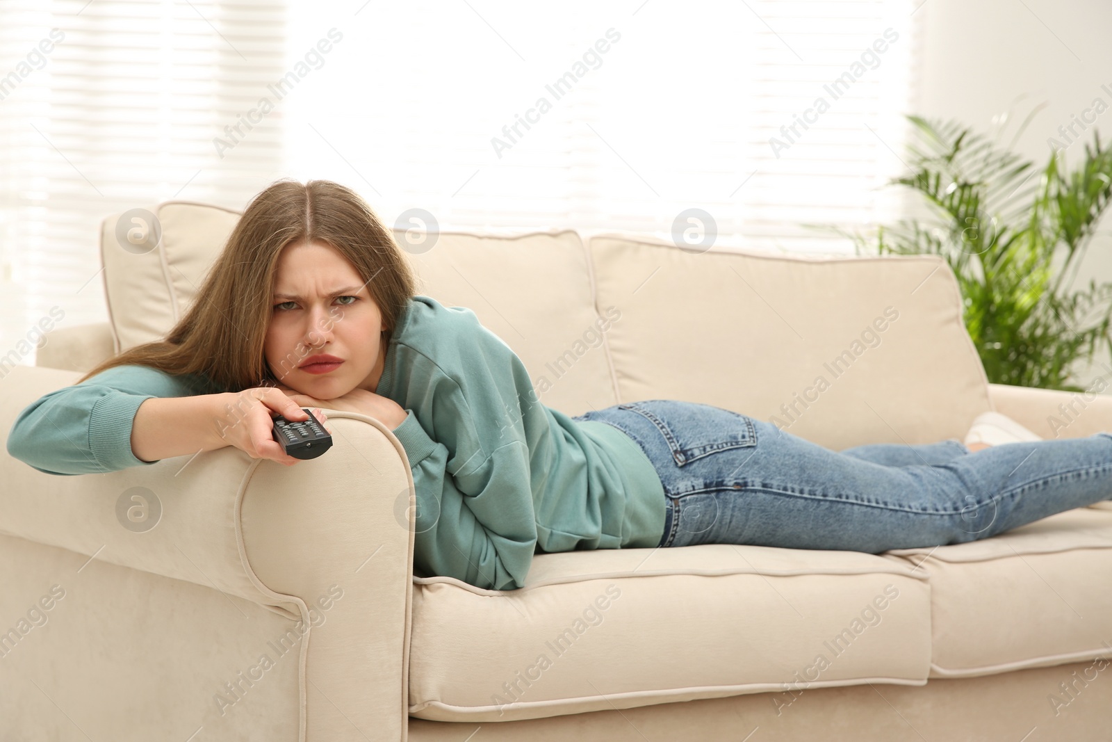 Photo of Lazy young woman watching TV on sofa at home