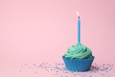 Photo of Delicious birthday cupcake with turquoise cream and burning candle on pink background. Space for text