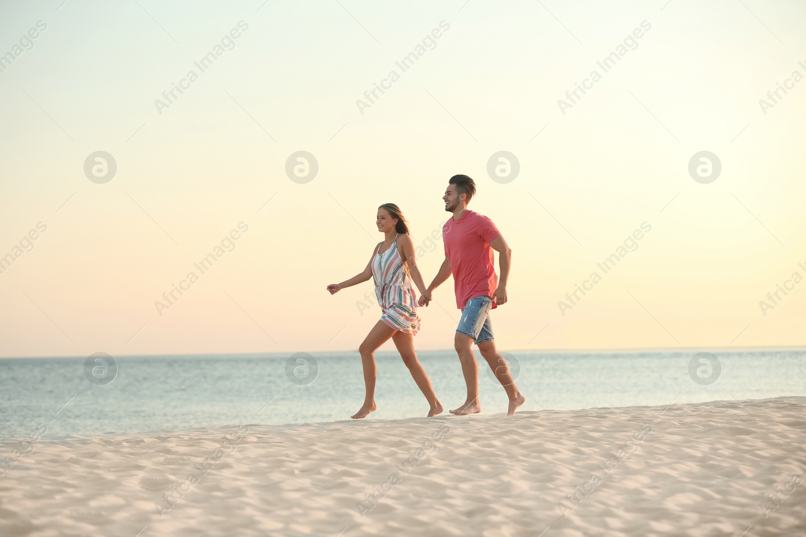 Photo of Happy young couple walking together on beach