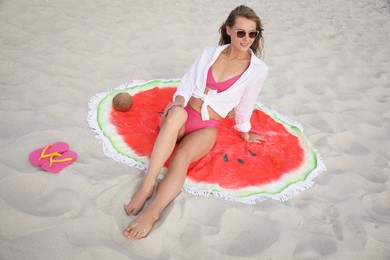 Beautiful woman with beach towel resting on sand