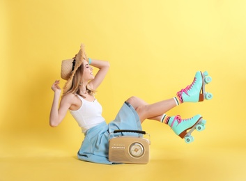 Young woman with roller skates and retro radio on color background