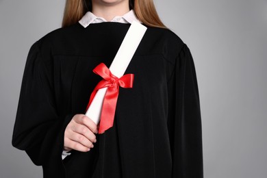 Photo of Student with diploma on grey background, closeup