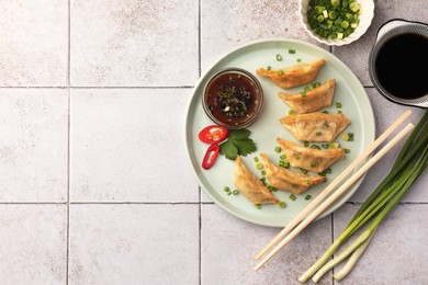 Photo of Delicious gyoza (asian dumplings) served on light tiled table, flat lay. Space for text
