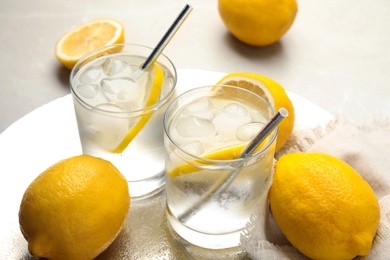 Soda water with lemon slices and ice cubes on table