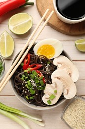 Photo of Tasty buckwheat noodles (soba) with egg and mushrooms served on wooden table, flat lay