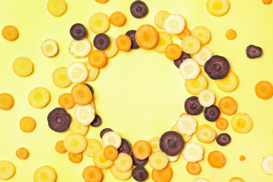 Photo of Frame of cut raw color carrots on yellow background, flat lay. Space for text