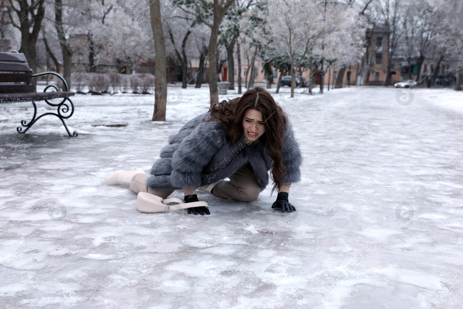 Photo of Young woman fallen on slippery icy pavement in park