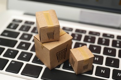 Image of Internet store. Small cardboard boxes with shopping carts on laptop, closeup