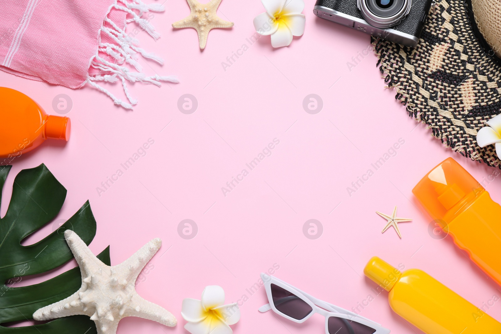 Photo of Frame made with sun protection products and beach accessories on pink background, flat lay. Space for text