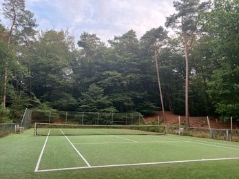 Photo of Tennis court with green grass and net outdoors