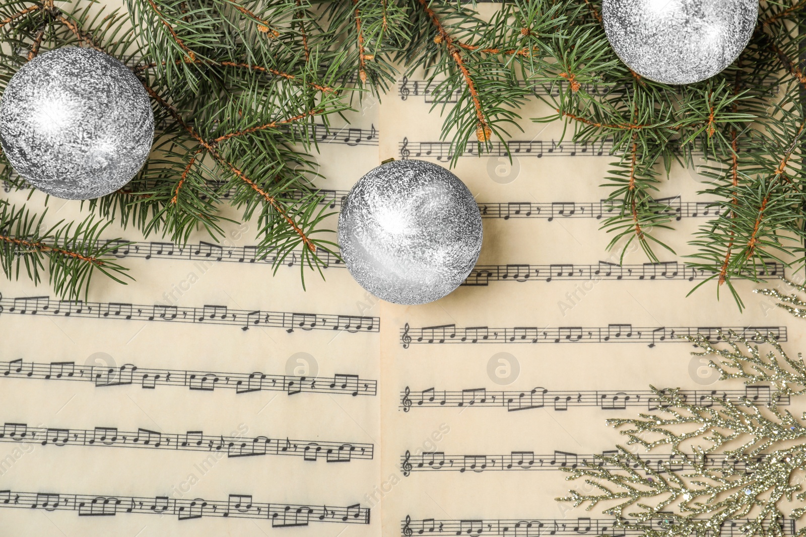 Photo of Composition with Christmas balls on music sheets, top view