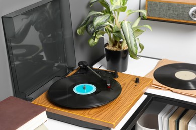 Stylish turntable with vinyl disc near grey wall in room