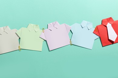 Photo of Many paper shirts on turquoise background, flat lay. Recruiter searching employee