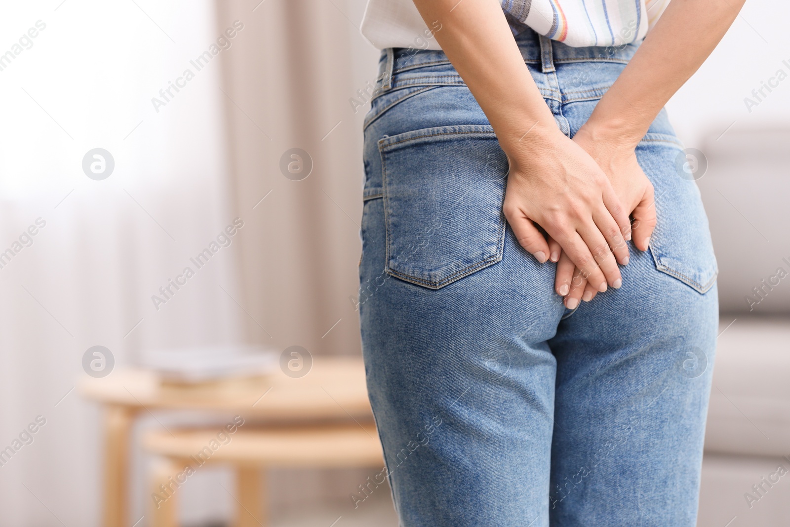 Photo of Young woman suffering from hemorrhoid at home, closeup