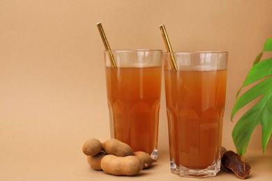 Tamarind juice, fresh fruits and green leaf on pale brown background, space for text