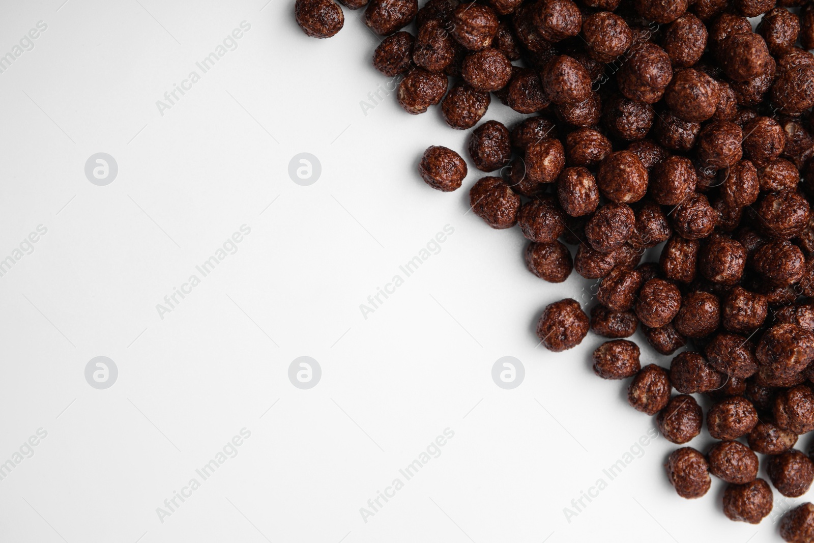 Photo of Tasty chocolate cereal balls on white background, flat lay. Space for text