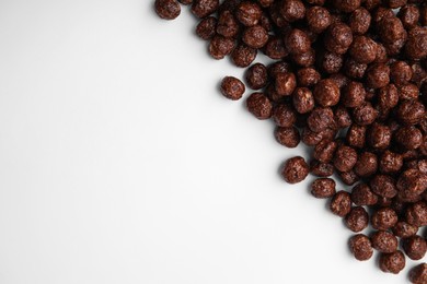 Photo of Tasty chocolate cereal balls on white background, flat lay. Space for text