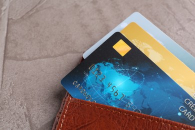 Photo of Credit cards in leather wallet on grey textured table, closeup