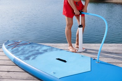 Photo of Man pumping up SUP board on pier, closeup