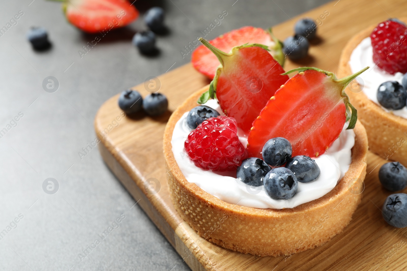 Photo of Delicious sweet pastries with berries on grey table. Space for text