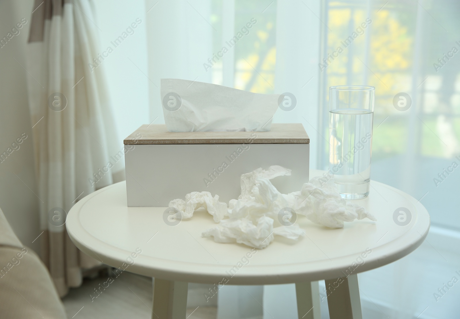 Photo of Used paper tissues, holder and water on table indoors