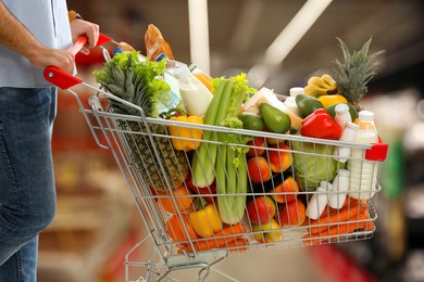 Image of Man with shopping cart full of groceries in supermarket, closeup