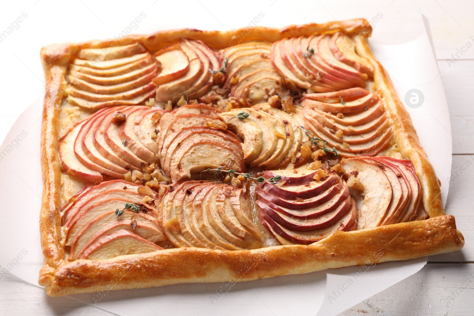Photo of Freshly baked apple pie with nuts on white wooden table, closeup