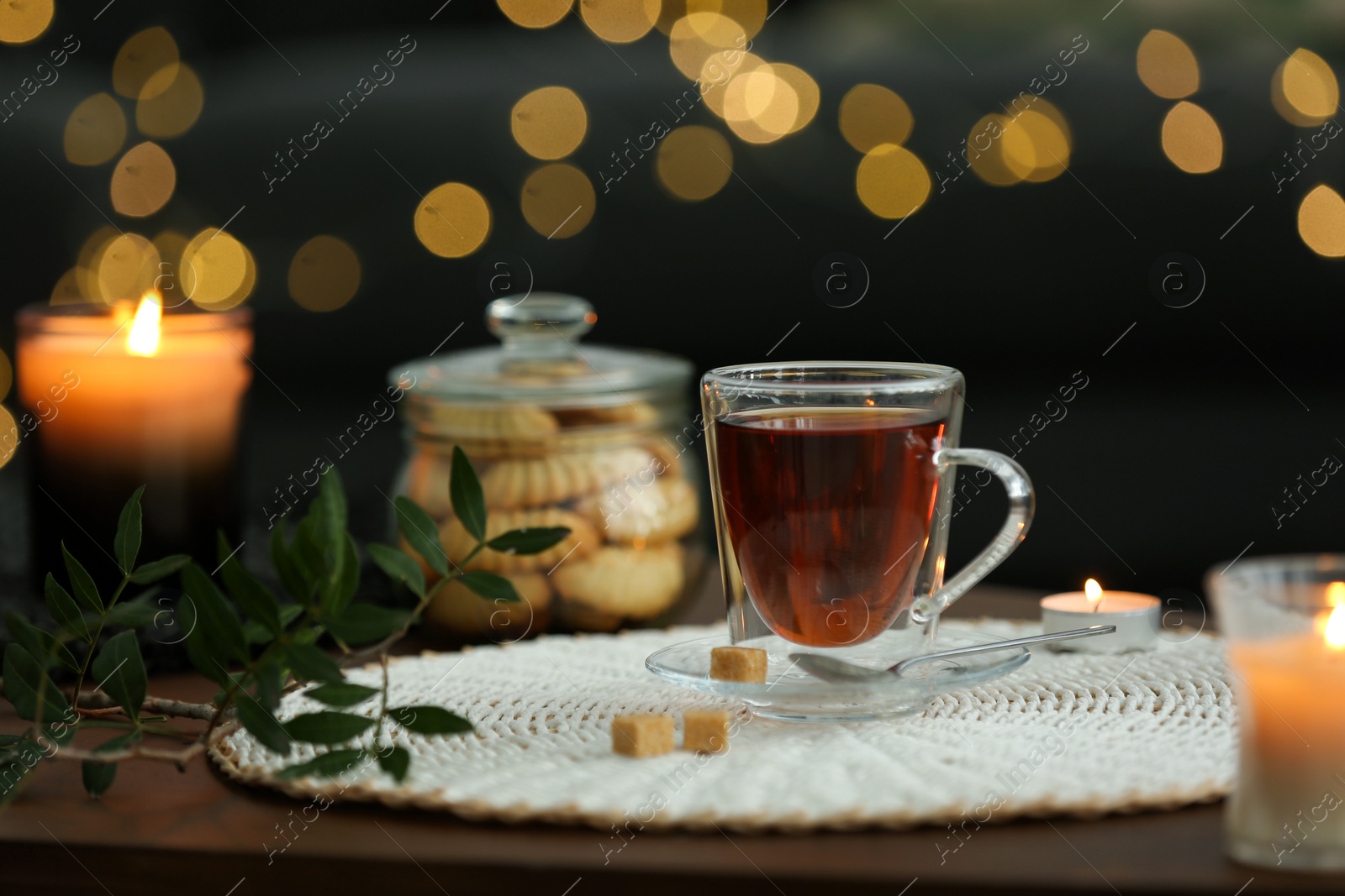 Photo of Tea, cookies and decorative elements on wooden table against blurred lights indoors