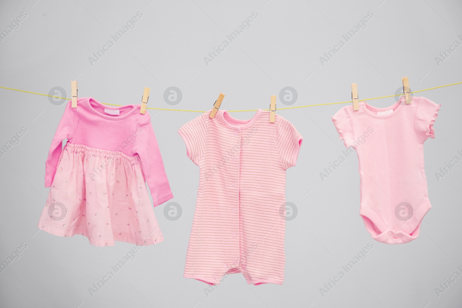 Photo of Baby clothes hanging on washing line against gray background