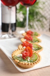 Delicious canapes with dry smoked sausages, cream cheese and vegetables on wooden table, closeup