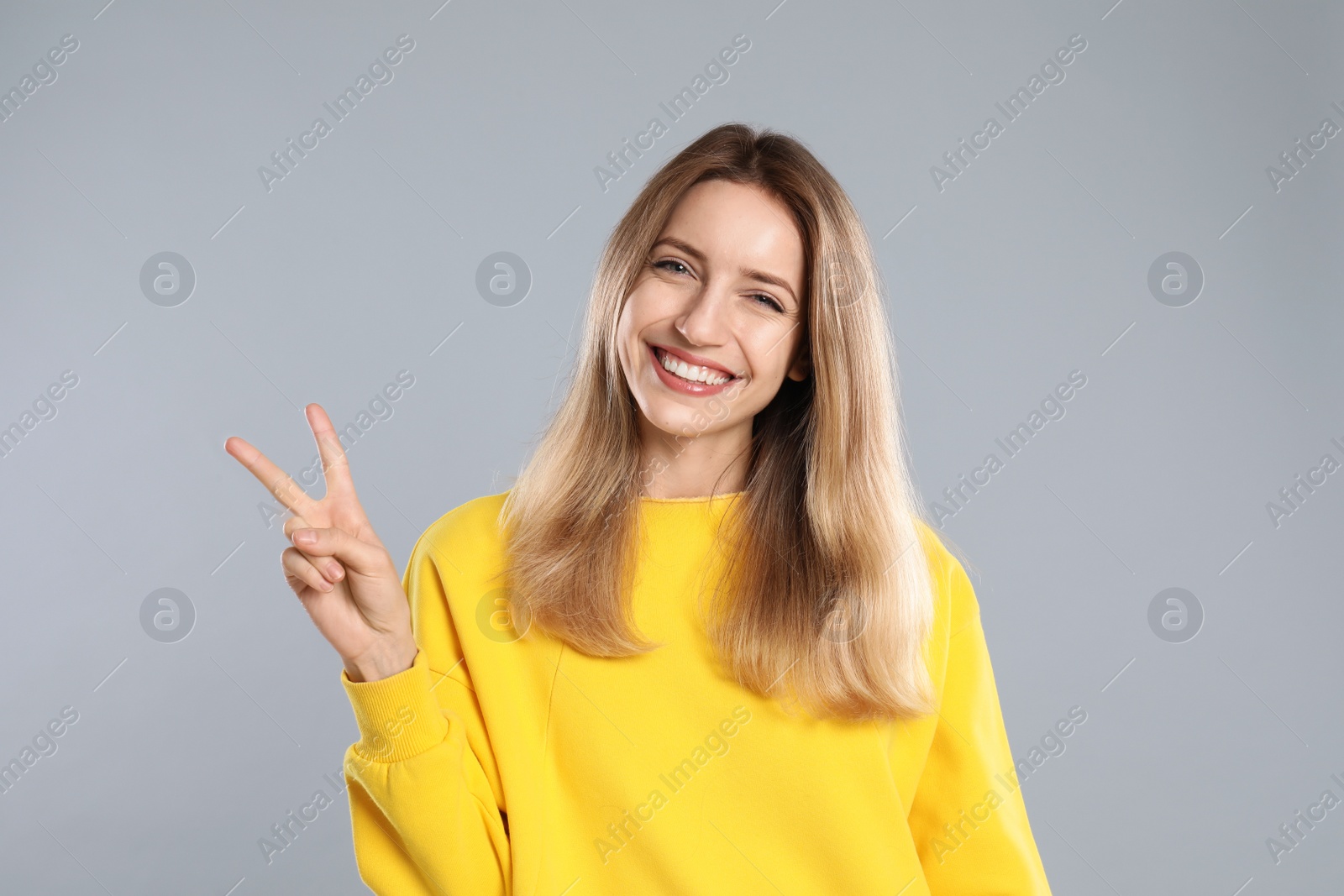 Photo of Woman showing number two with her hand on light grey background