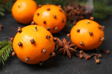 Photo of Delicious fresh tangerines with cloves on black table, closeup. Christmas celebration