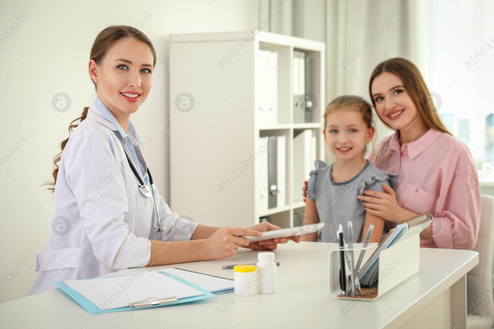 Photo of Mother and daughter visiting pediatrician. Doctor working with patient in hospital