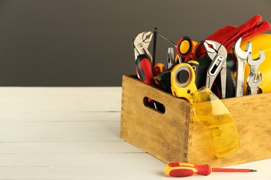 Photo of Wooden box with different tools for repair on white table, space for text