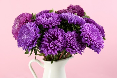Photo of Beautiful asters in jug on pink background, closeup. Autumn flowers