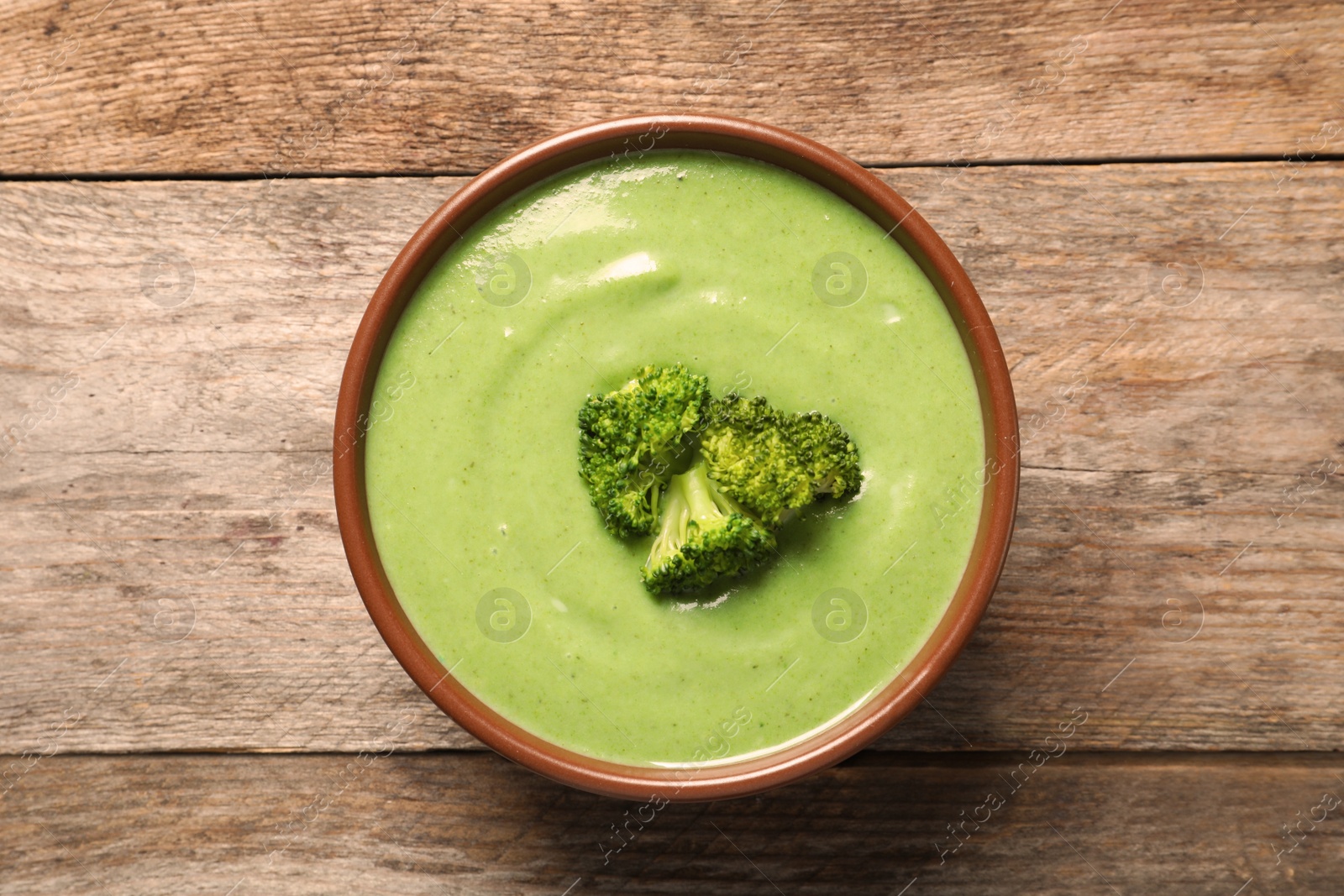 Photo of Fresh vegetable detox soup made of broccoli in dish on wooden background, top view