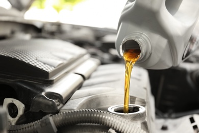 Photo of Pouring oil into car engine, closeup