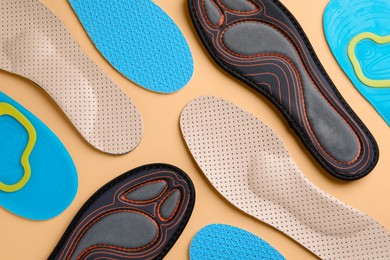 Photo of Many different shoe insoles on pale orange background, flat lay