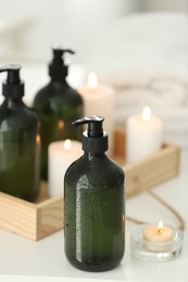 Photo of Wooden tray with soap dispensers and burning candles on white table