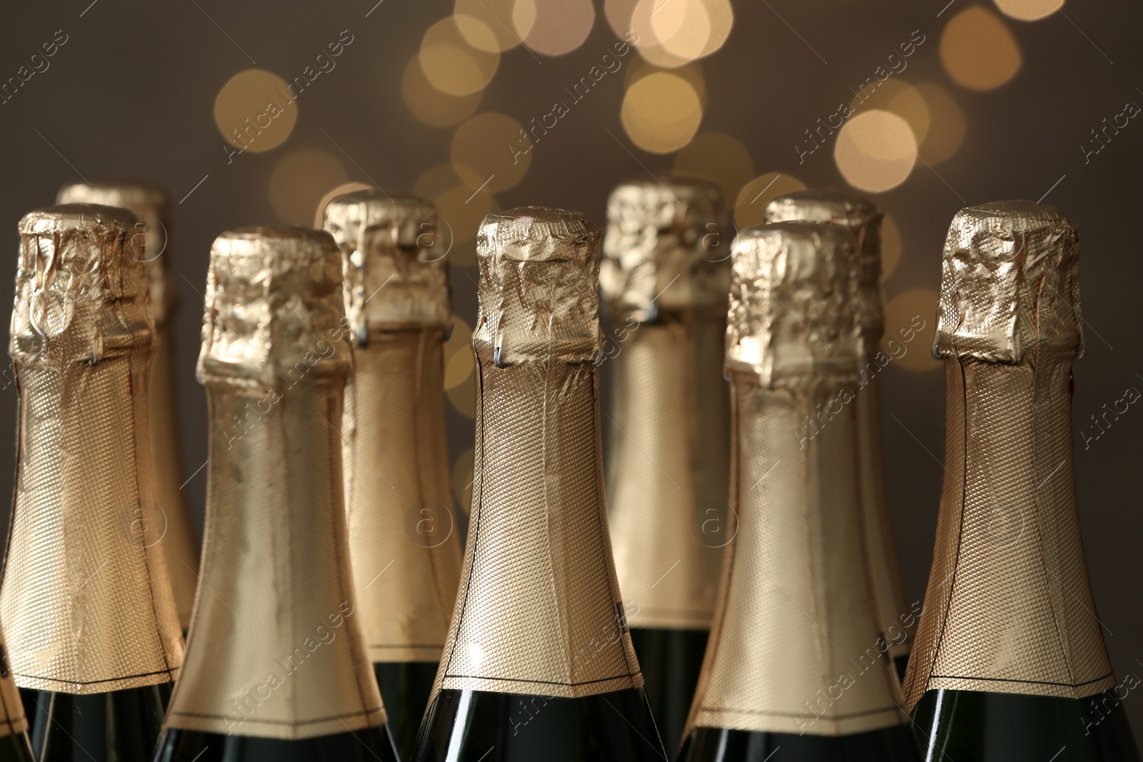 Photo of Many bottles of champagne on blurred background, closeup