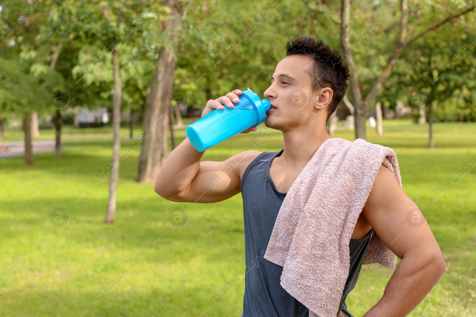 Photo of Young man drinking protein shake in park