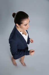 Young businesswoman in elegant suit on grey background, above view