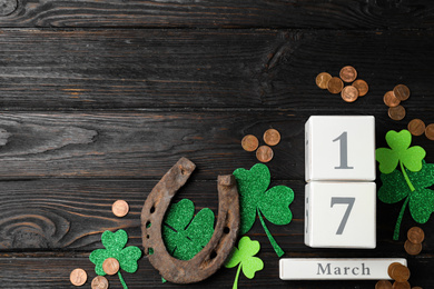 Photo of Flat lay composition with horseshoe and block calendar on black wooden background, space for text. St. Patrick's Day celebration