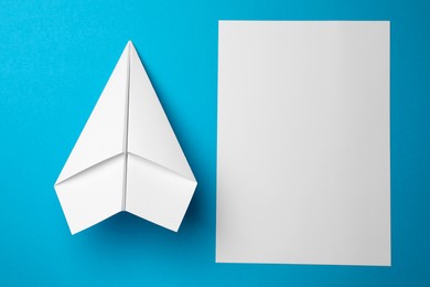 Photo of Handmade plane and piece of paper on light blue background, flat lay